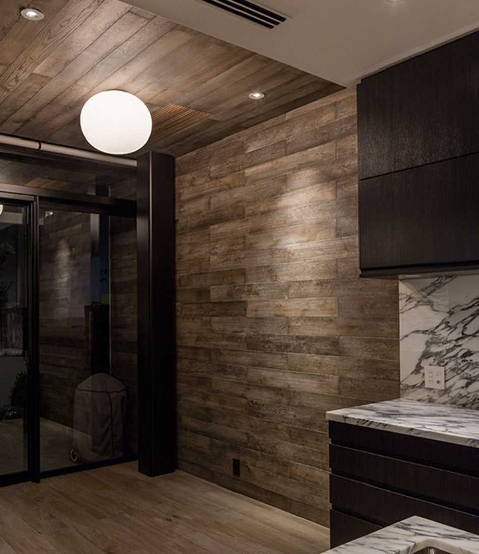 Flos Glo-Ball ceiling sconce mounted to the ceiling in a wood-panelled room.