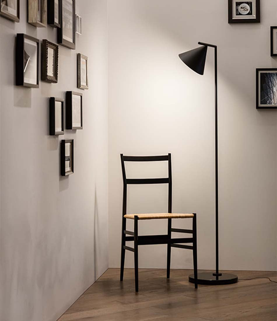 Black Flos Captain Flint floor lamp illuminating a chair in the corner of a room.