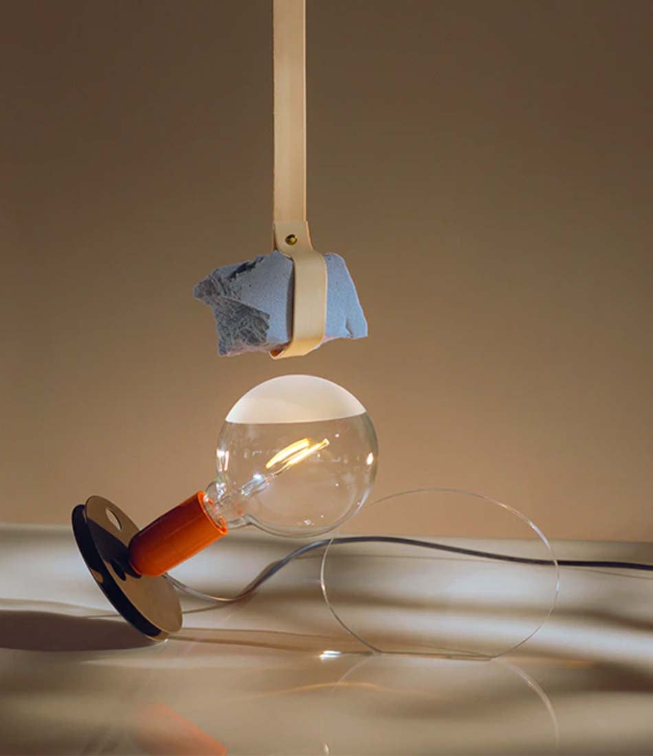 Flos Lampadina table lamp. A film spool base supports a naked halogen bulb in an orange cylindrical socket.