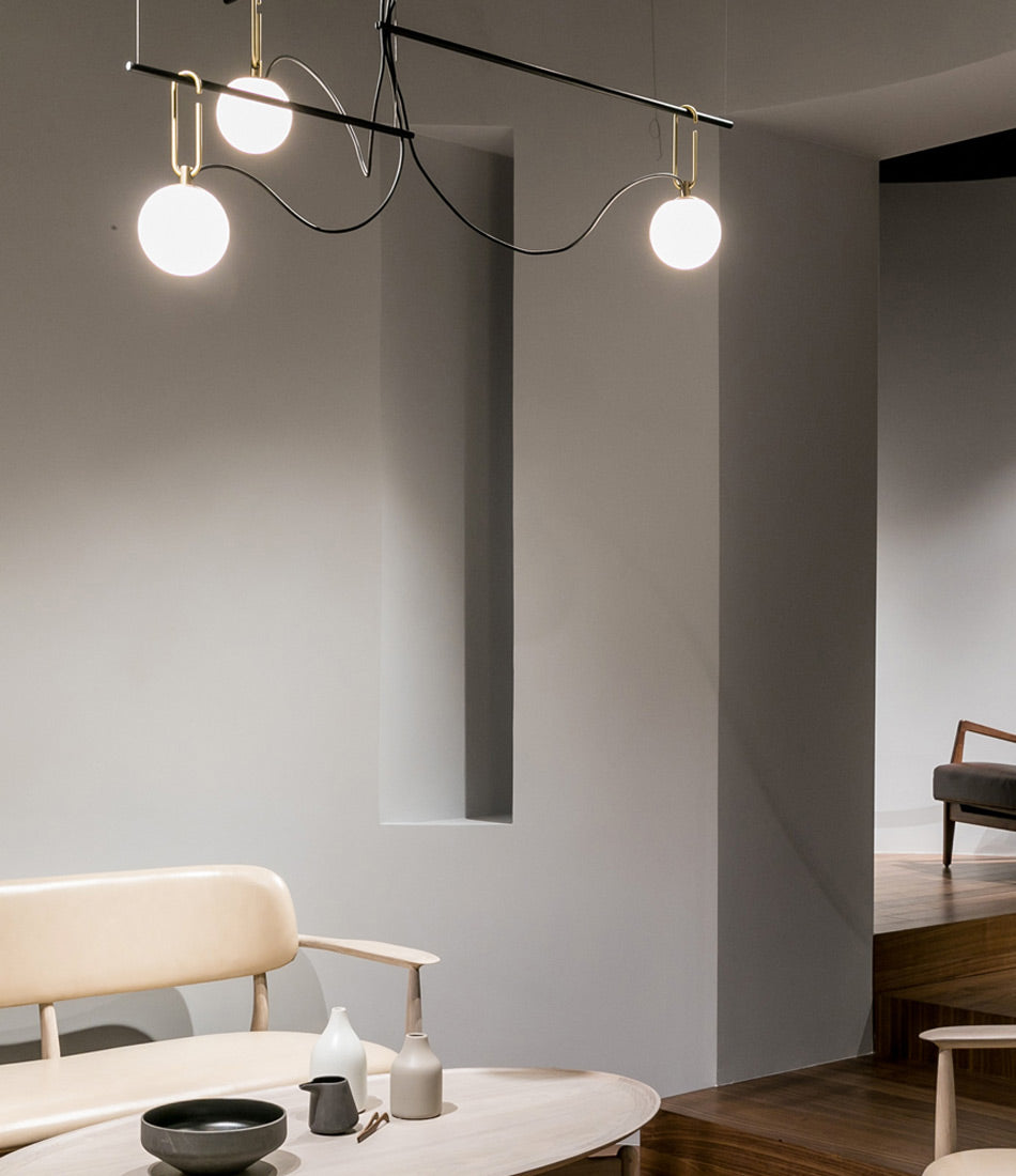 Artemide NH S3 suspension lamp hanging over coffee table containing ceramic dishes.