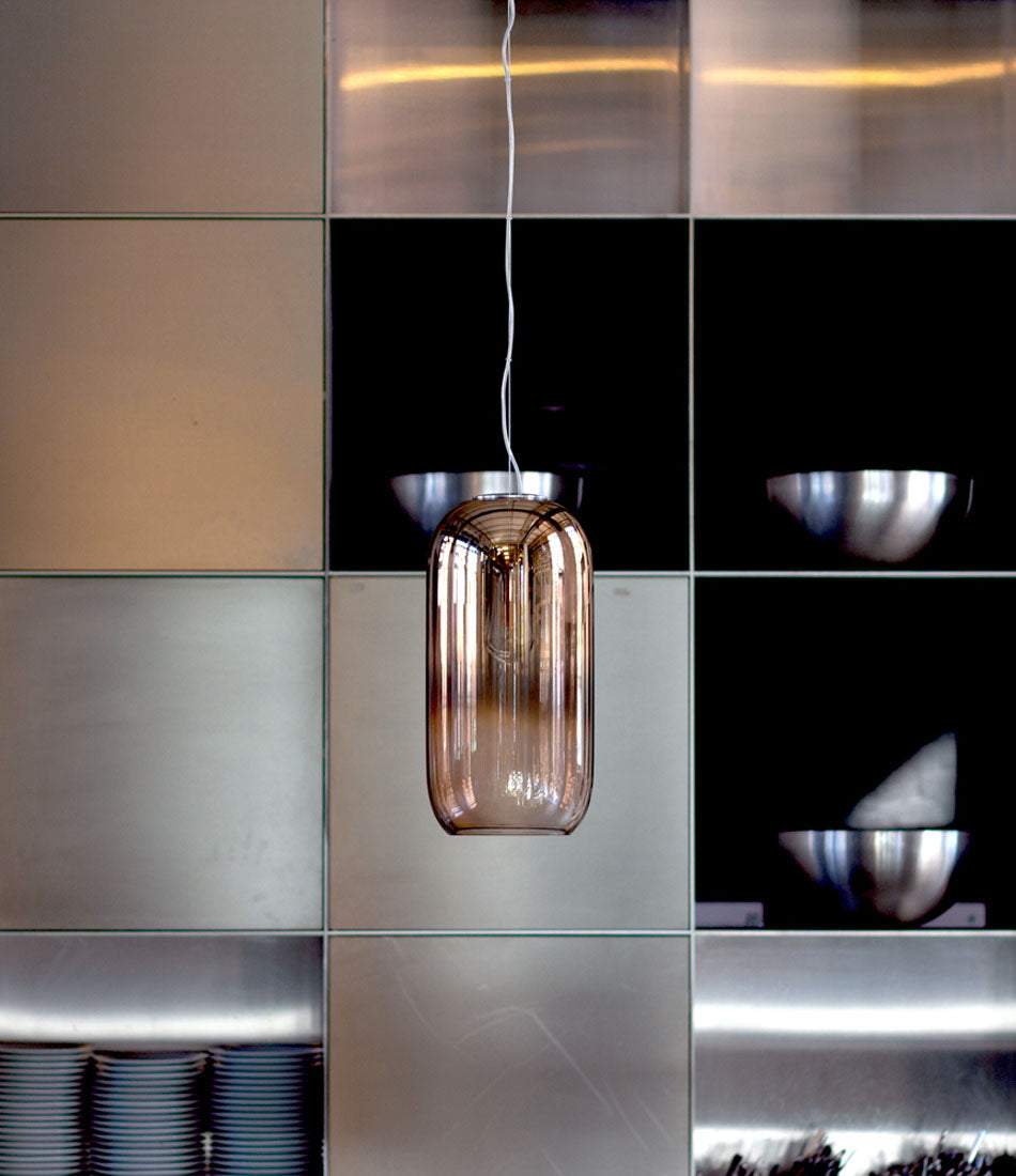 Bronze Artemide Gople Suspension light hanging in front of a tile wall.