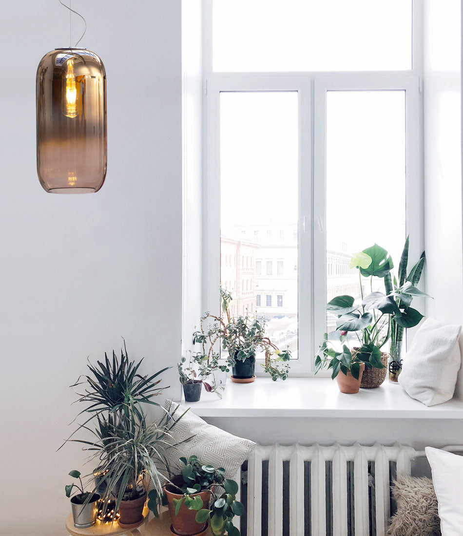 Bronze Artemide Gople suspension light beside a window with plants on a ledge.