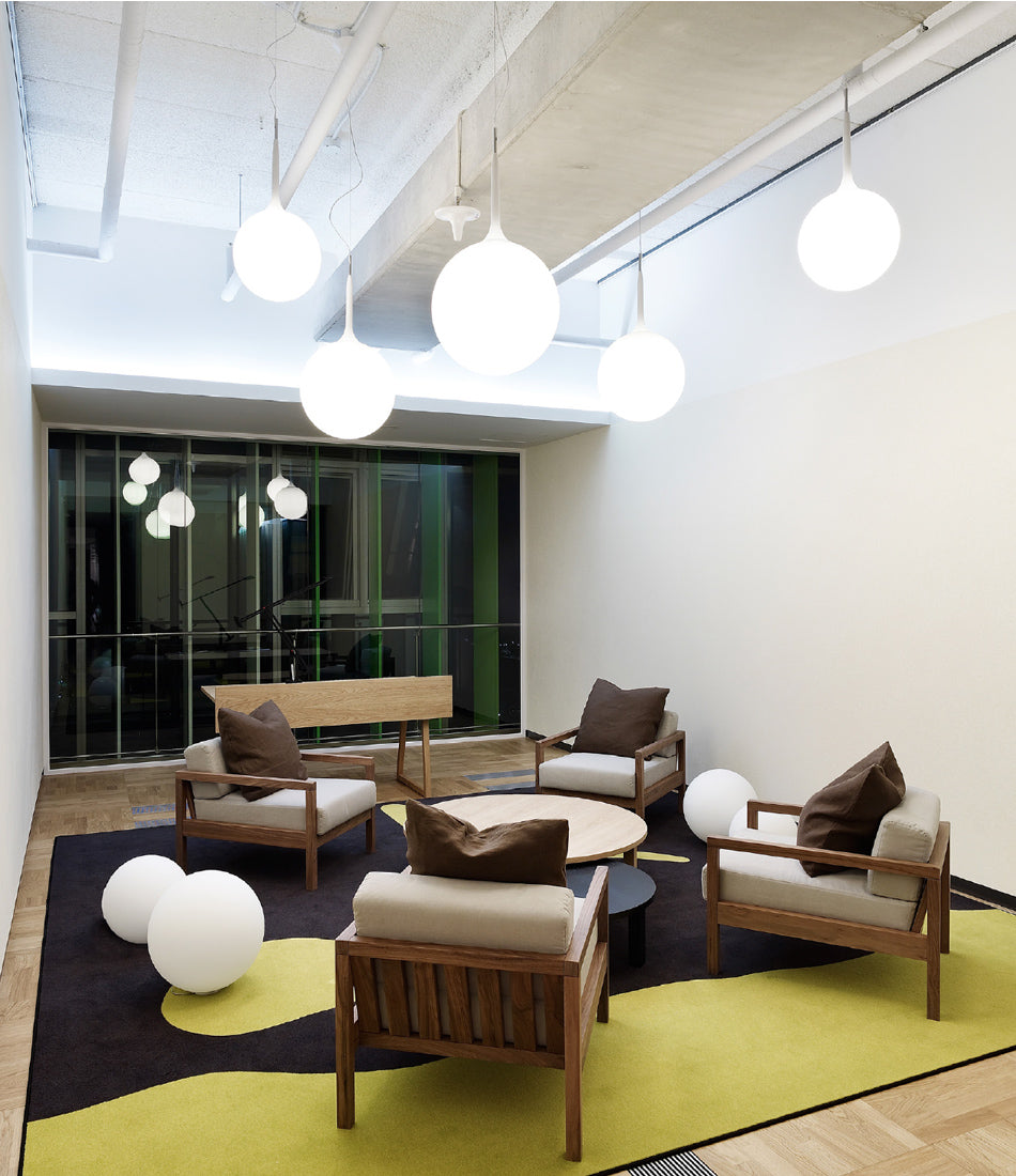 Multiple Artemide Castore Suspension lamps hanging above a carpeted lounge area.