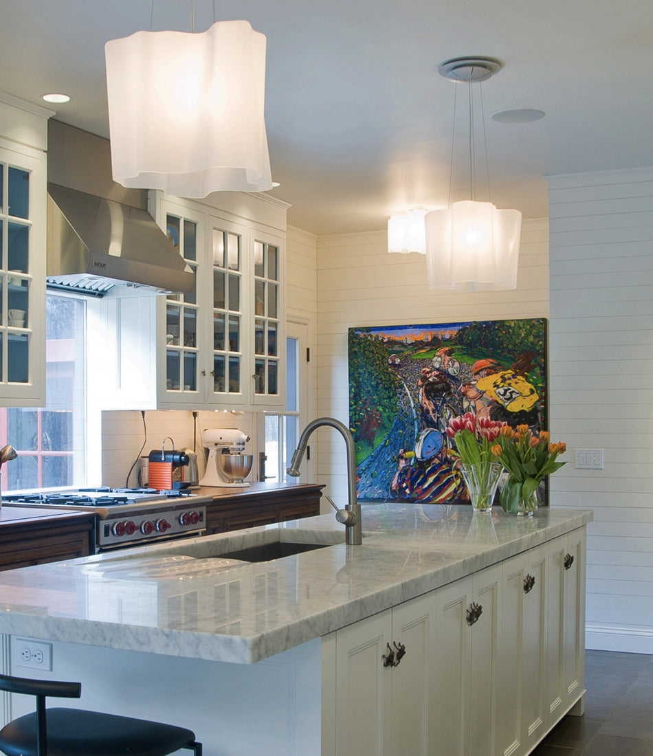 Two milky white Artemide Logico Single suspension lamps above a kitchen island.