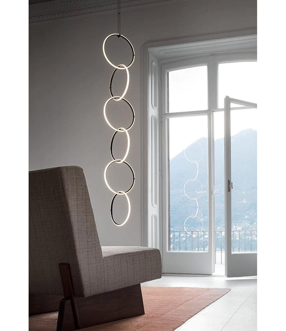 Flos Arrangements Suspension Light 6 hangs in a living room corner, next to glass patio doors.