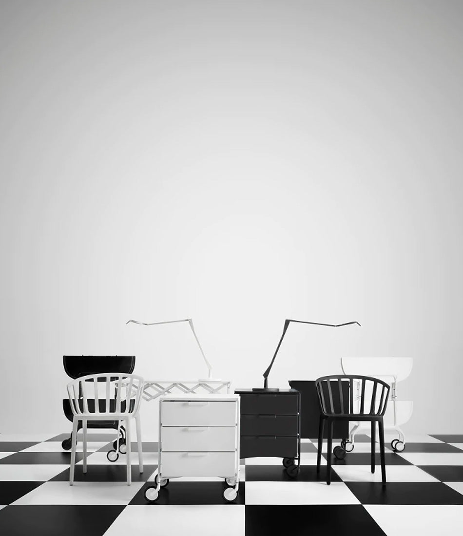 Mobile Kartell drawer storage cart next to chairs on a checkered floor.