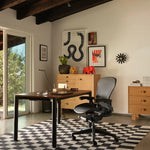 Modern office setup with a Herman Miller desk, Aeron Remastered chair, and Nelson decorative prints.