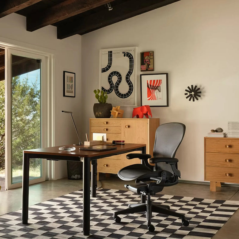 Modern office setup with a Herman Miller desk, Aeron Remastered chair, and Nelson decorative prints.