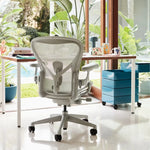 Aeron Remastered ergonomic office chair,  Everywhere table, Flos Bellhop, and Magis 360 Degree Container in a modern office setting with plants.
