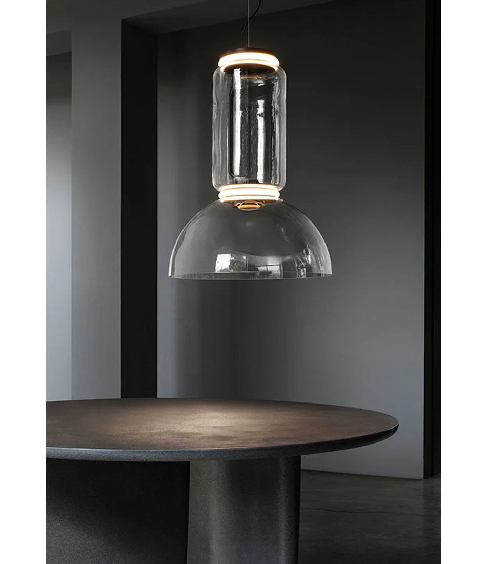 Flos Noctambule suspension lamp above a stone table. Glass bowl bottom and glass cylinder stem.