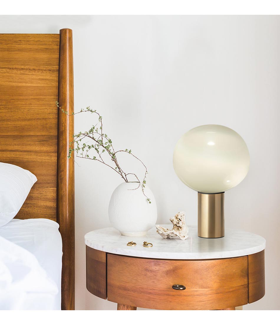 Artemide satin brass Laguna table lamp on a wooden bedside table.