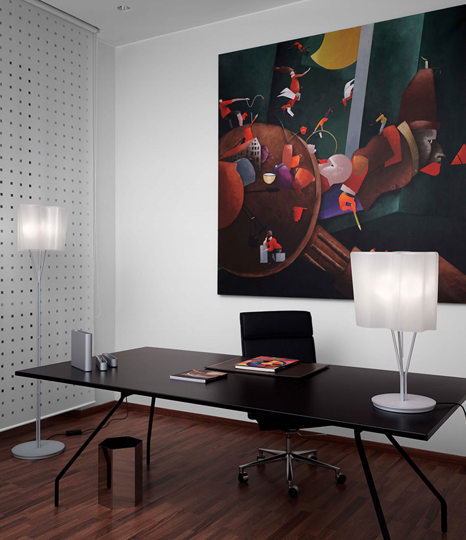 Artemide Logico table lamp on an office desk in front of a large painting.