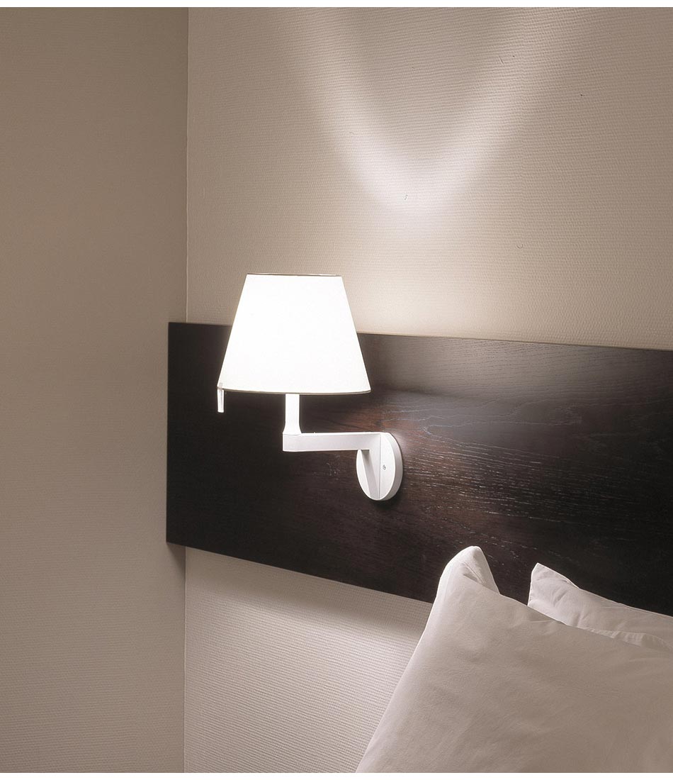 Artemide Melampo Mini wall lamp mounted to a wood board above a bed.