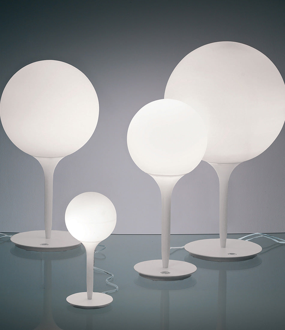 Group of Artemide Castore table lamps of various sizes on a glass surface.