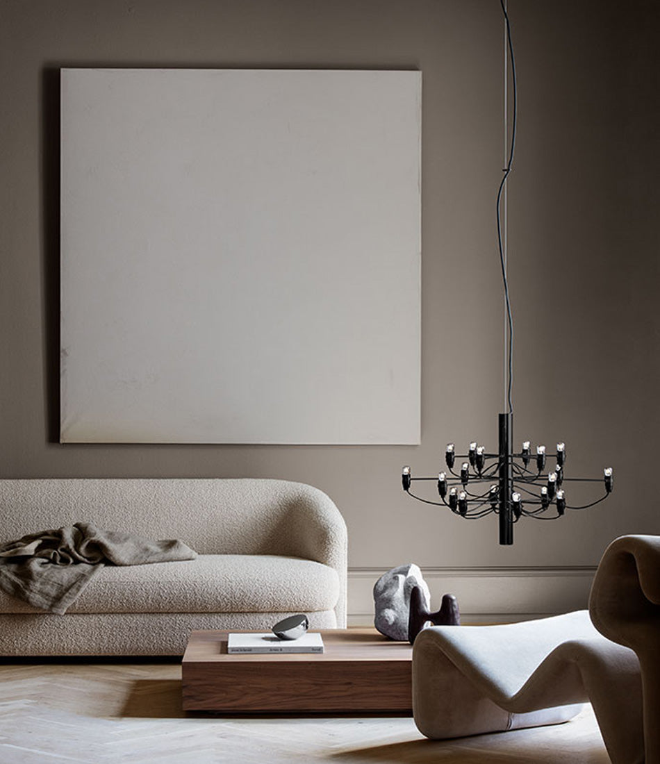Flos 2097/18 suspension lamp hangs low above a wood coffee table, next to a sofa and lounge chair in a living room.