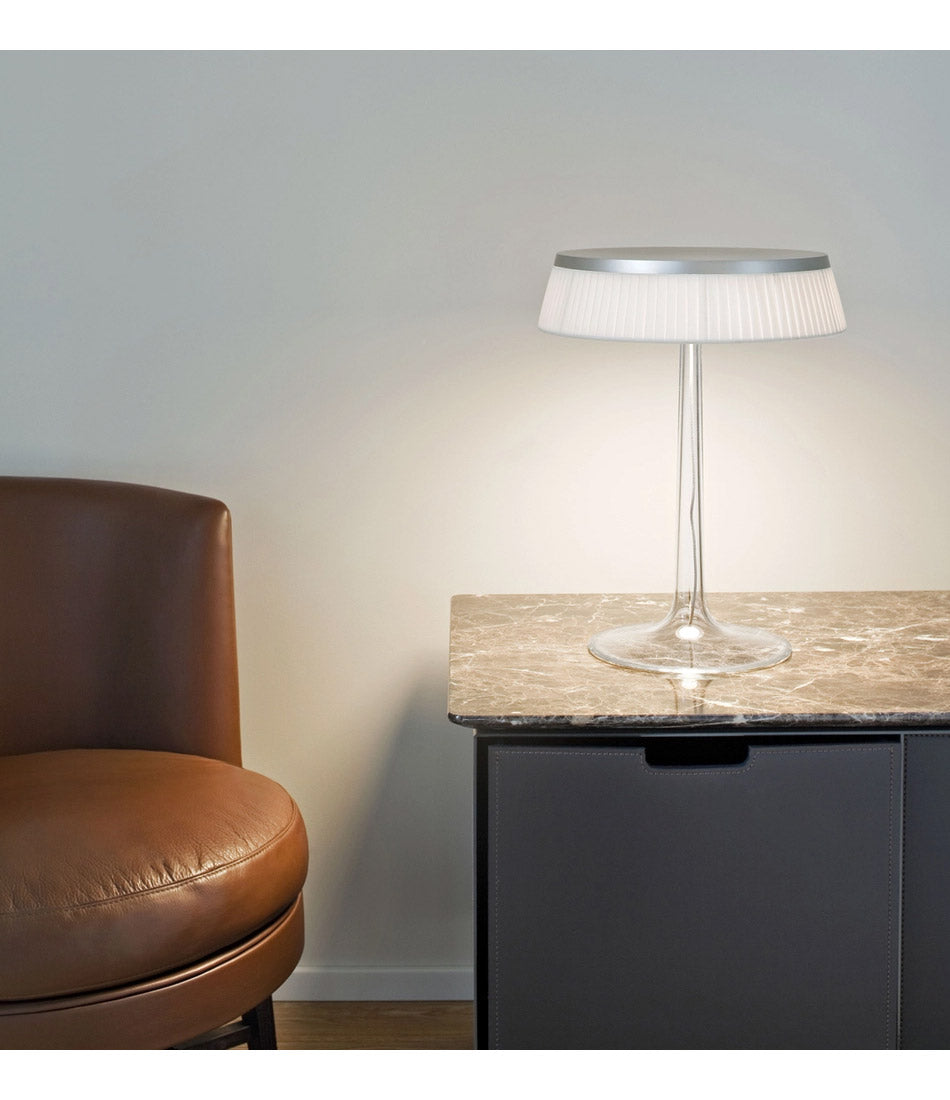 Flos Bon Jour table lamp on a marble-topped cabinet next to a leather lounge chair.