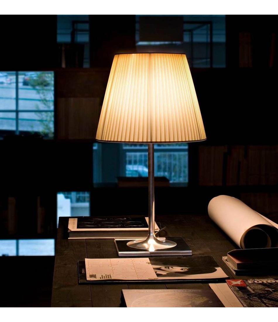 Flos KTribe table lamp with cloth lampshade on a desk with magazines and papers.