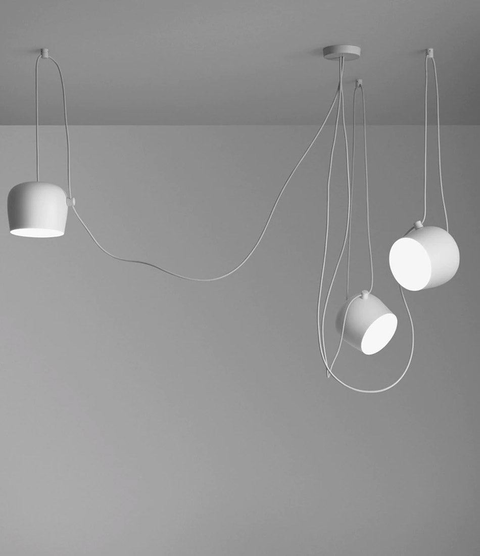 Three small white Flos AIM pendant lamps hanging in sequence from a ceiling.