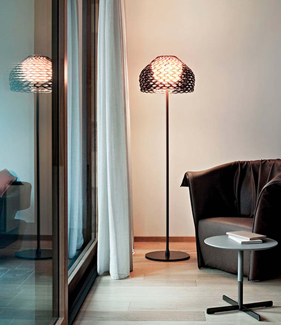 Flos Tatou floor lamp next to a lounge chair beside a window.